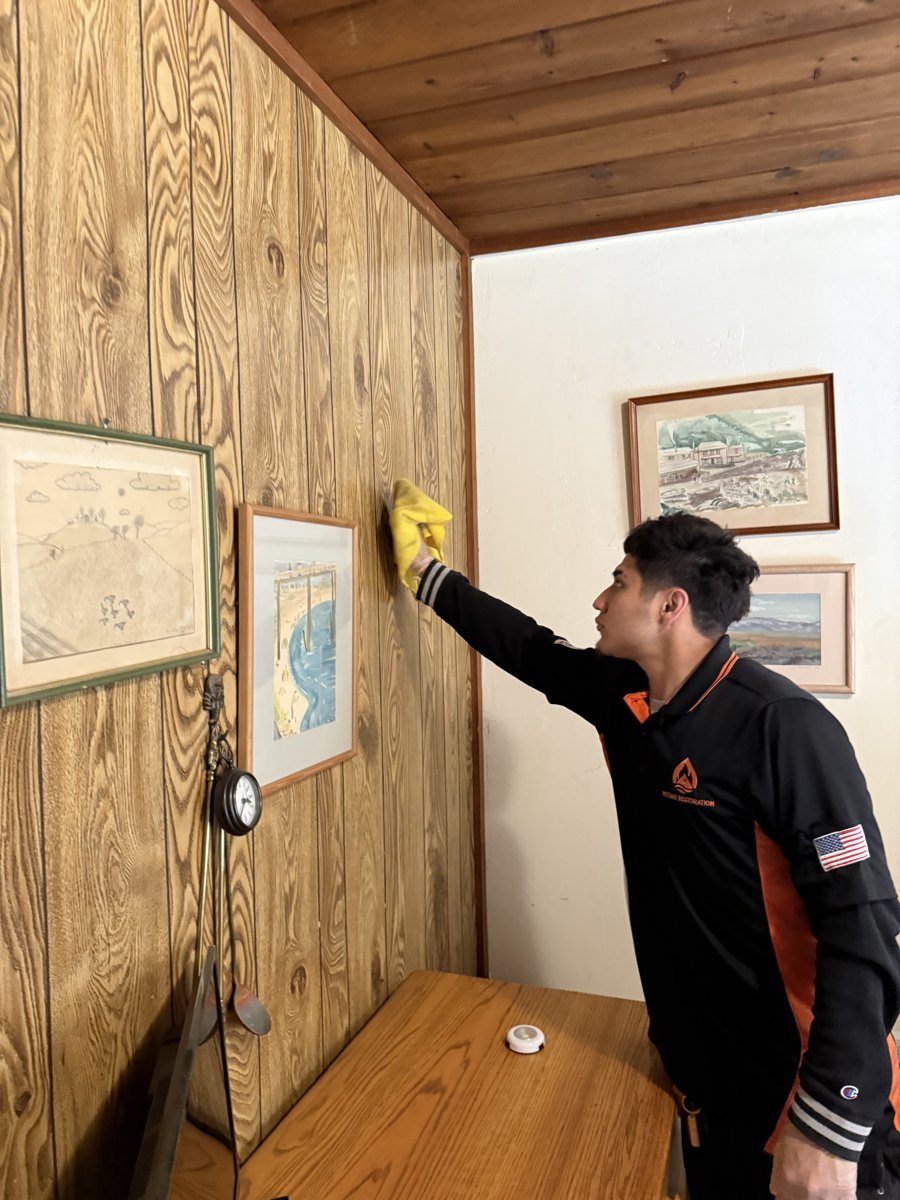 Technician cleaning smoke residue from wood wall paneling - porous wood holds smoke odor - Camarillo, CA