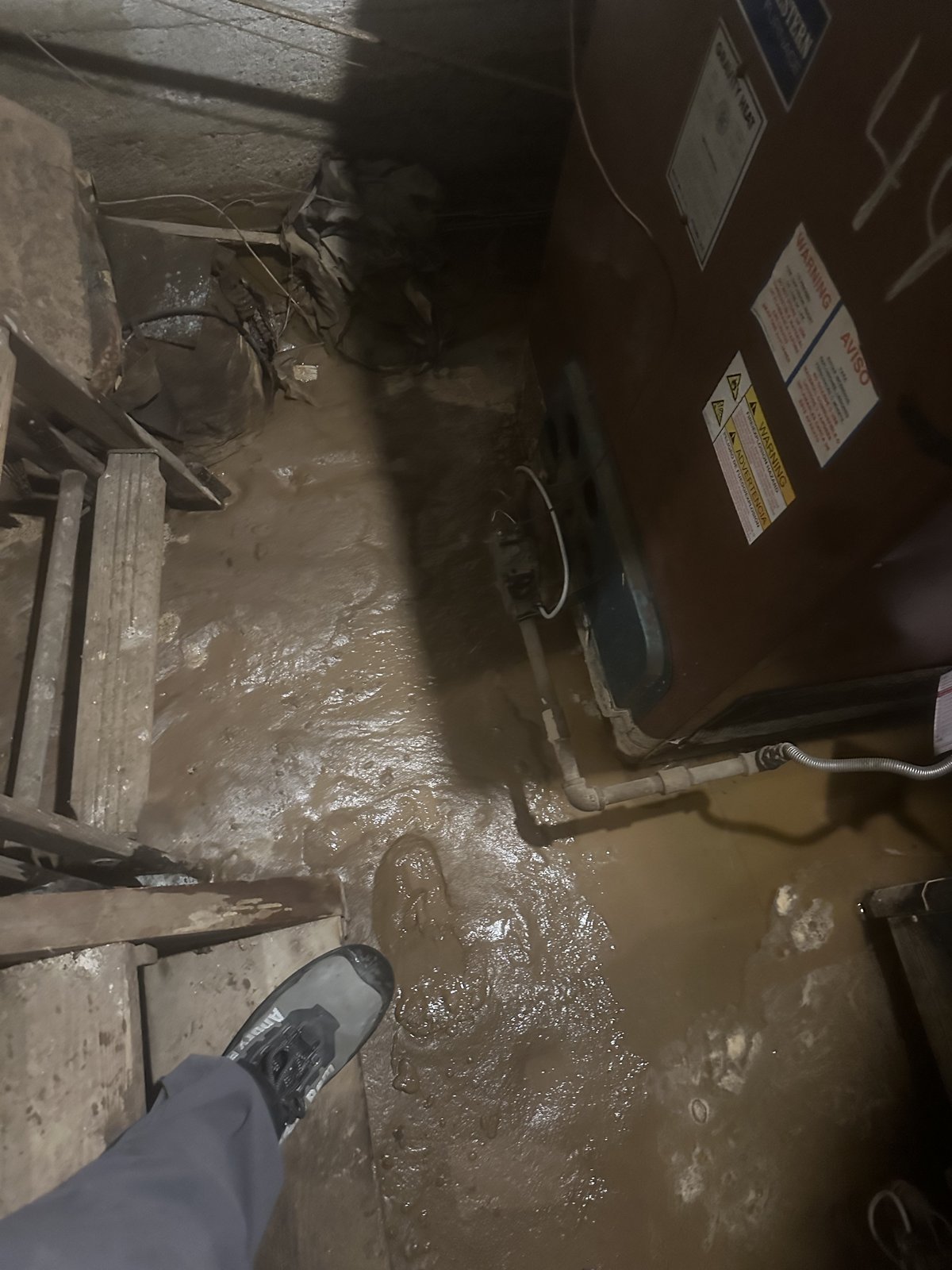 Storm mud covering a flooded basement floor around the furnace after heavy rains - flood damage cleanup in Los Angeles, CA