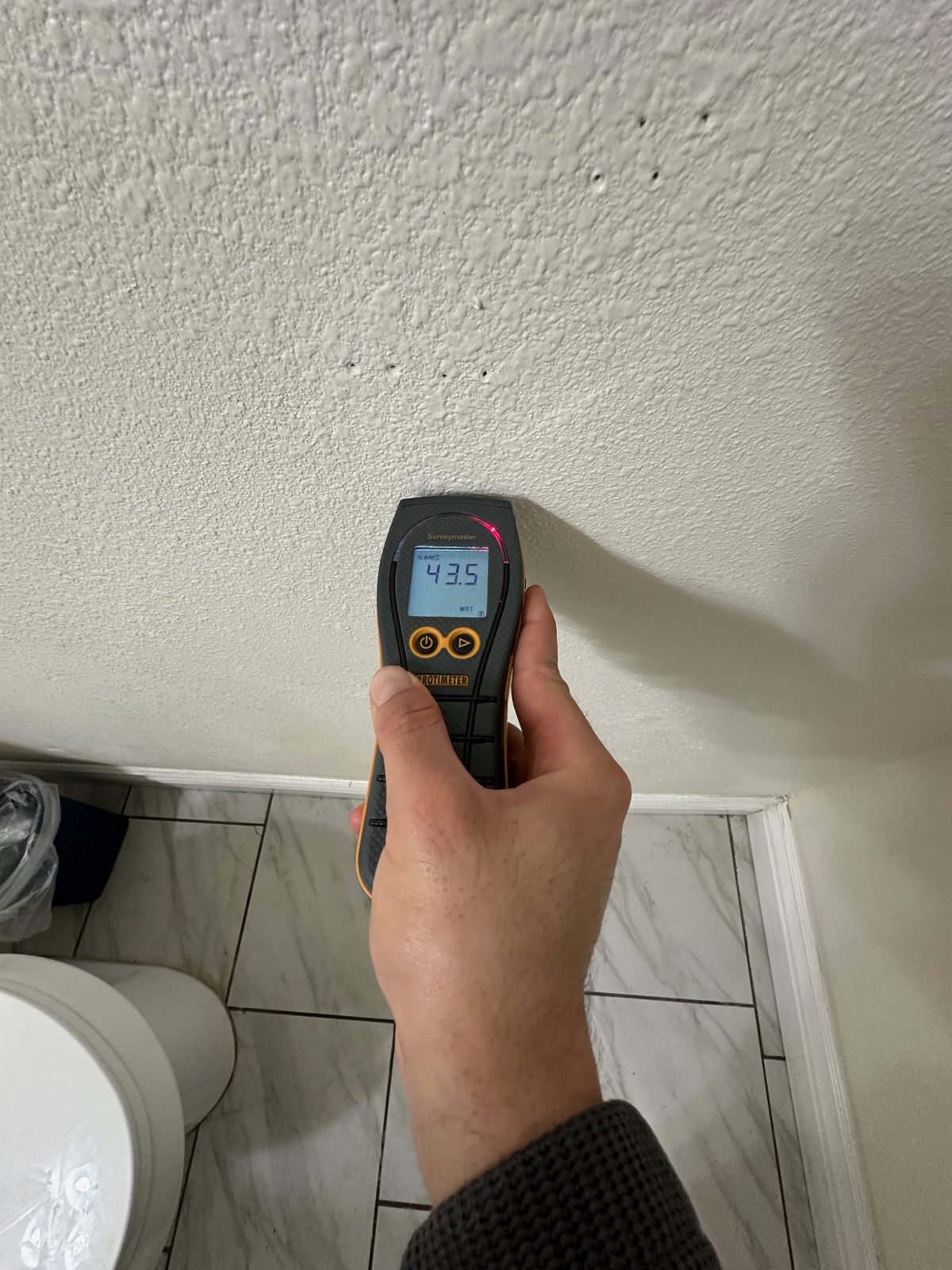 Lectura de medidor de humedad en la pared del baño durante la documentación del daño - Oxnard, CA