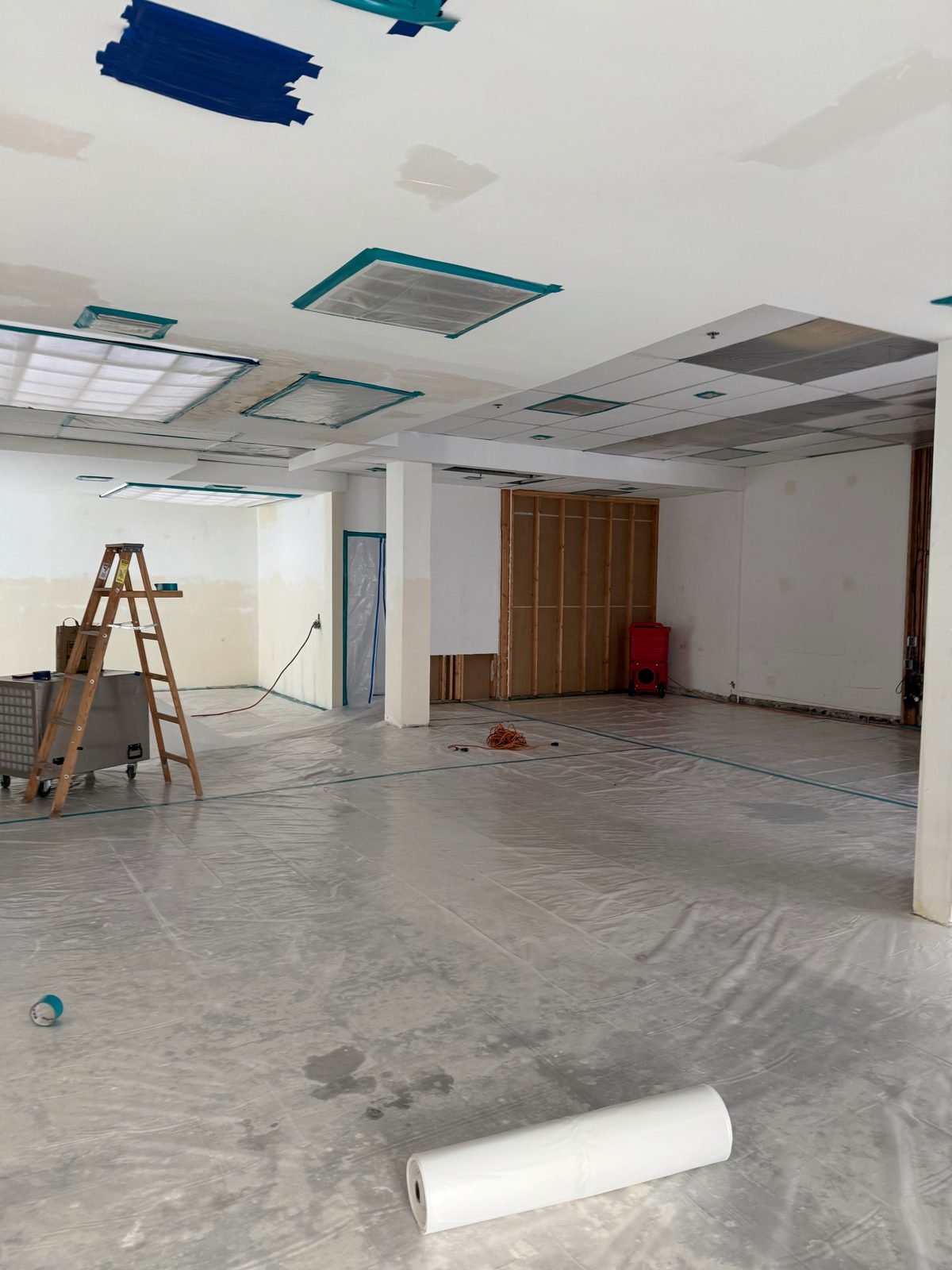 Instant Restoration job photo in Malibu, CA: Open commercial floor with poly sheeting, ladder, ceiling grid, red equipment