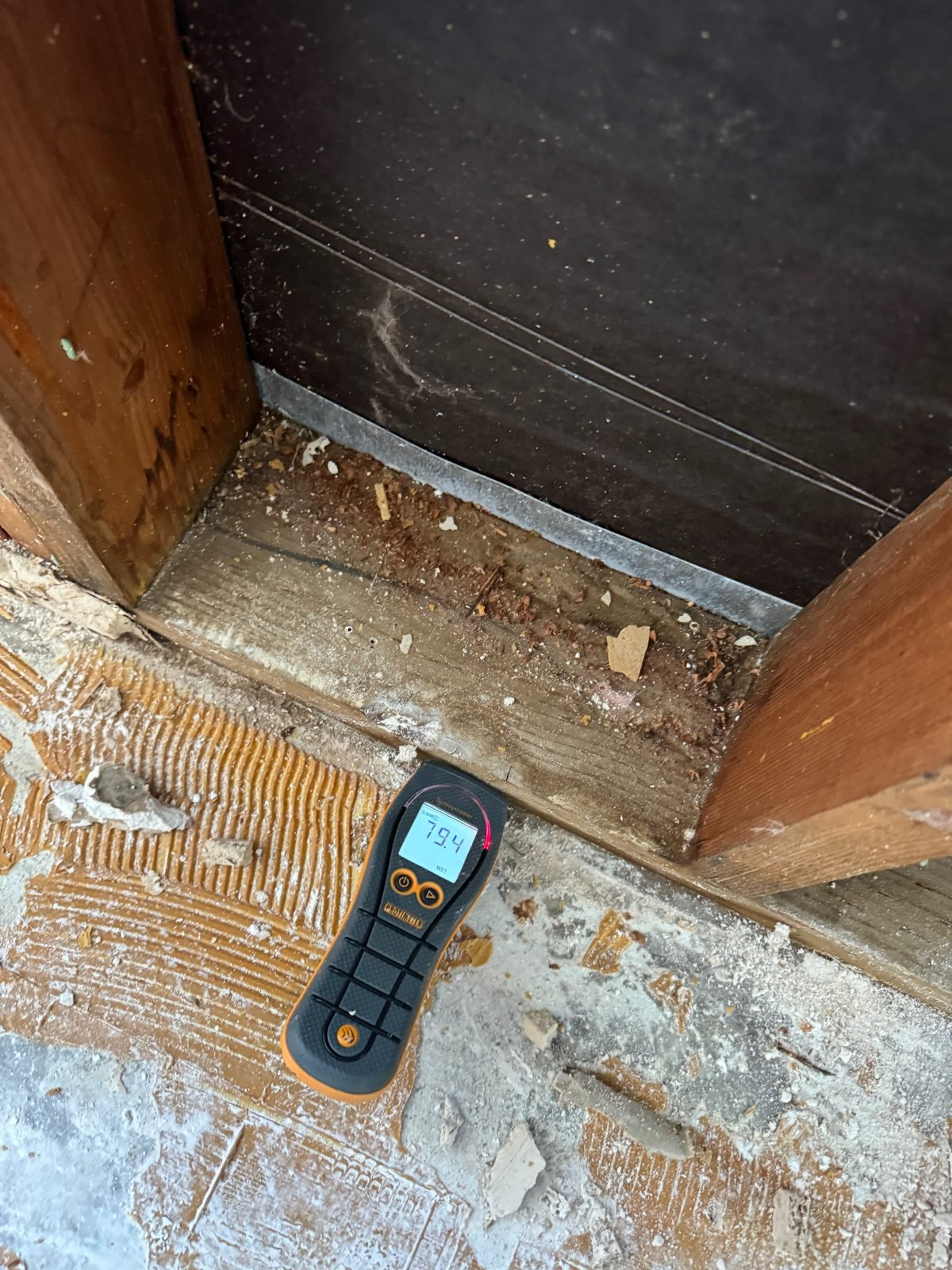 Instant Restoration job photo in Calabasas, CA: Moisture meter reading on stripped floor beside framing and wet wood