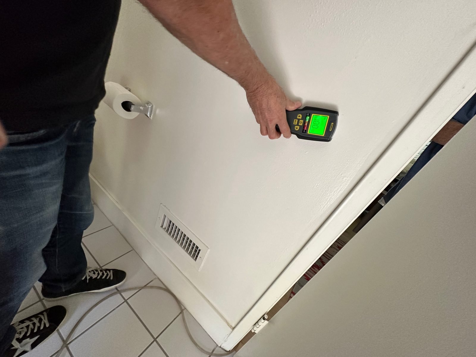Instant Restoration job photo in Brentwood, CA: Technician scanning wall near baseboard with moisture meter; face not visible