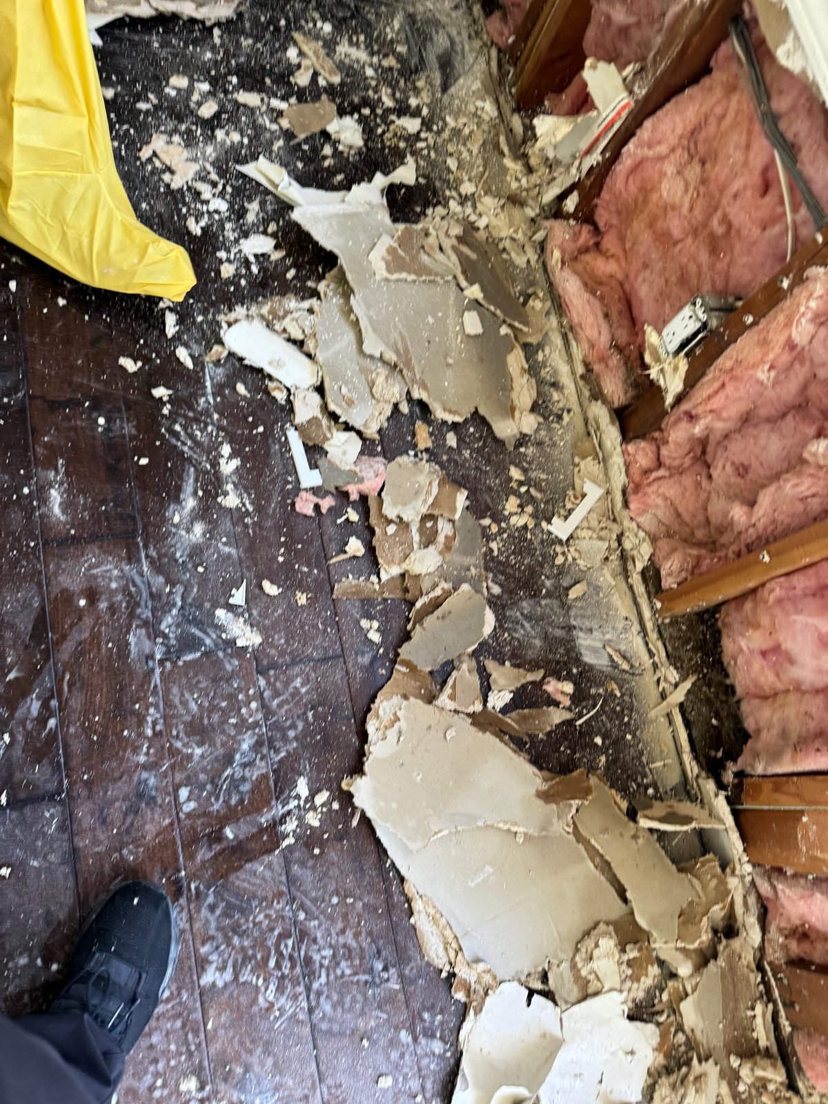 Instant Restoration job photo in Calabasas, CA: Demo debris: broken drywall, pink insulation, floor; crew shoe at corner