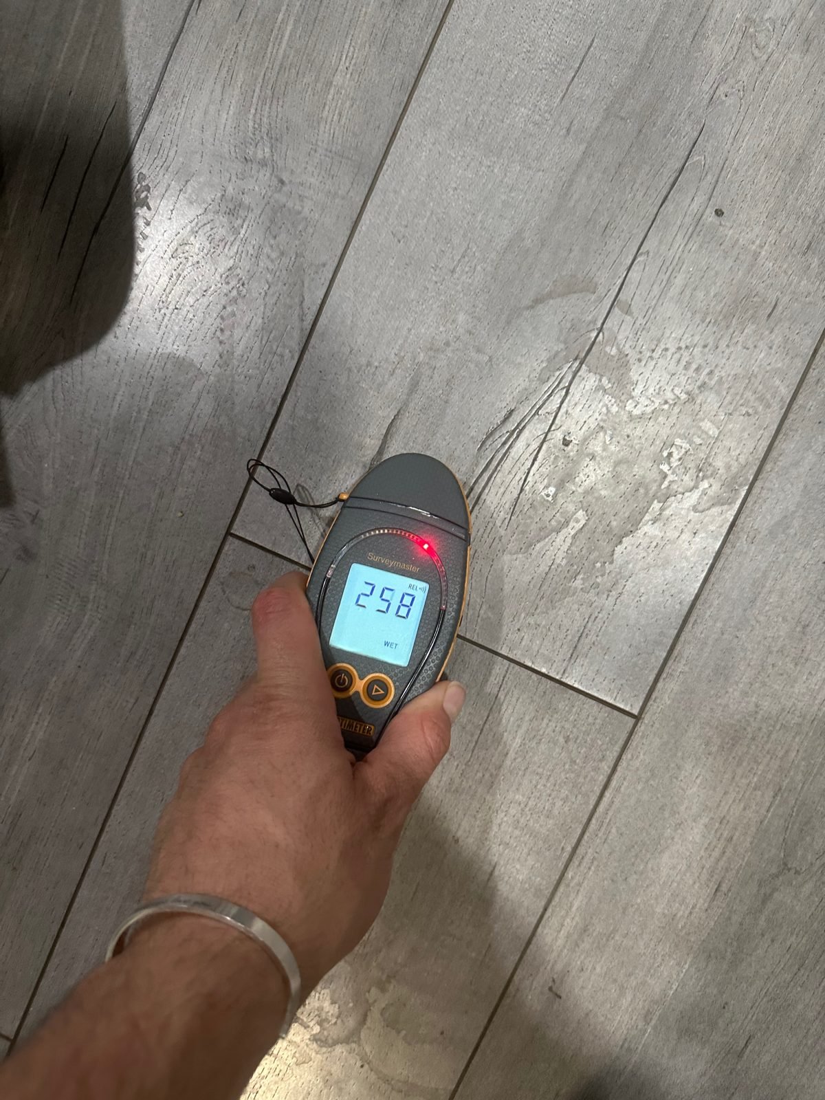 Moisture meter reading WET on water-stained plank flooring - Oxnard, CA