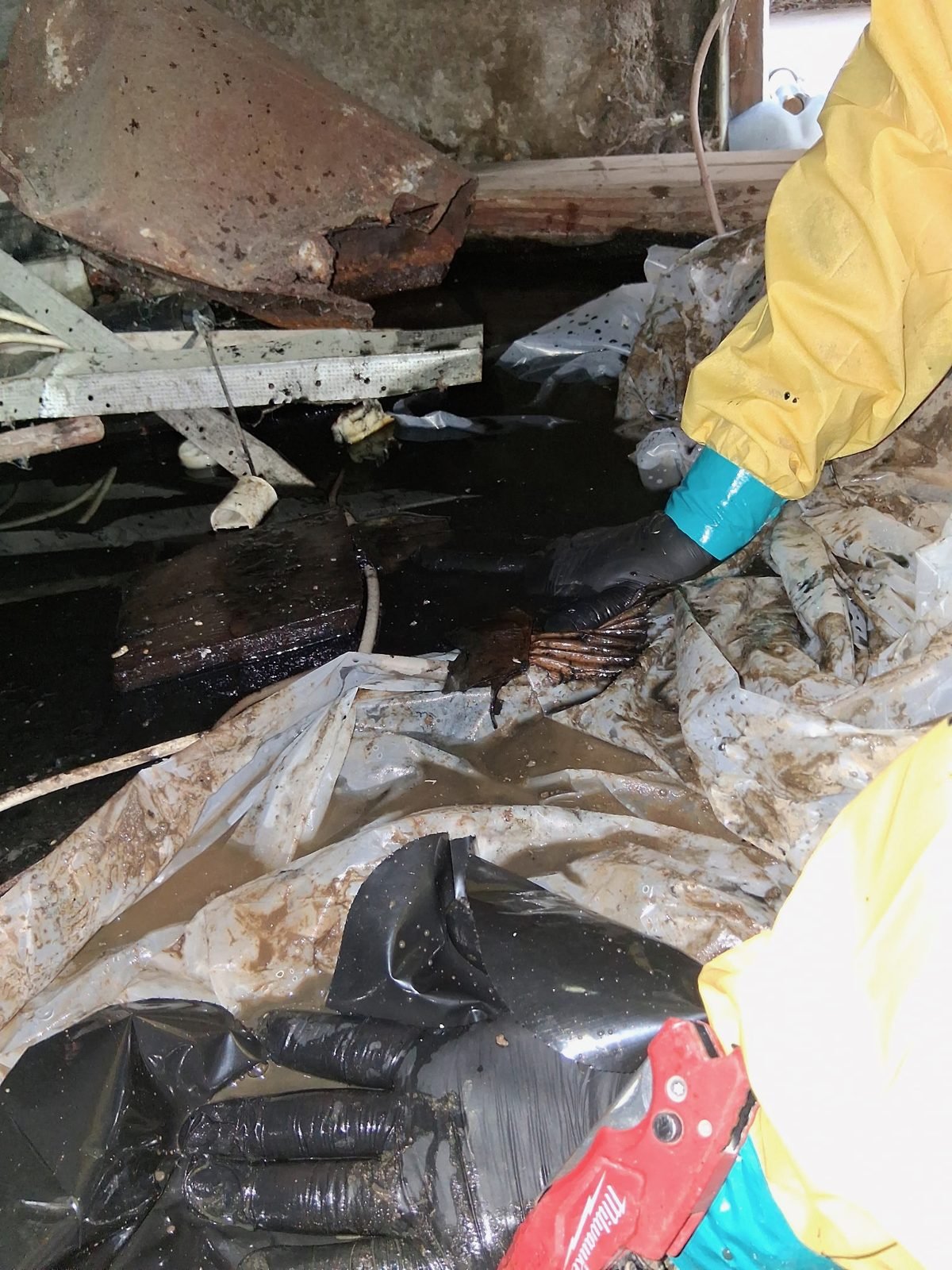 Instant Restoration job photo in Beverly Hills, CA: Crew in yellow suit pumping flooded crawlspace, face not visible